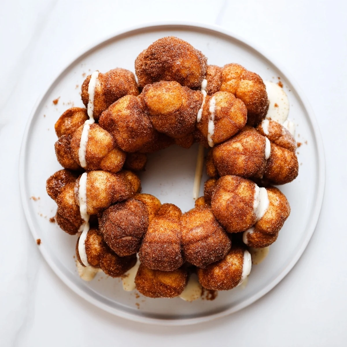 Pull-apart sugar-free monkey bread balls drizzled with vanilla glaze on a serving plate