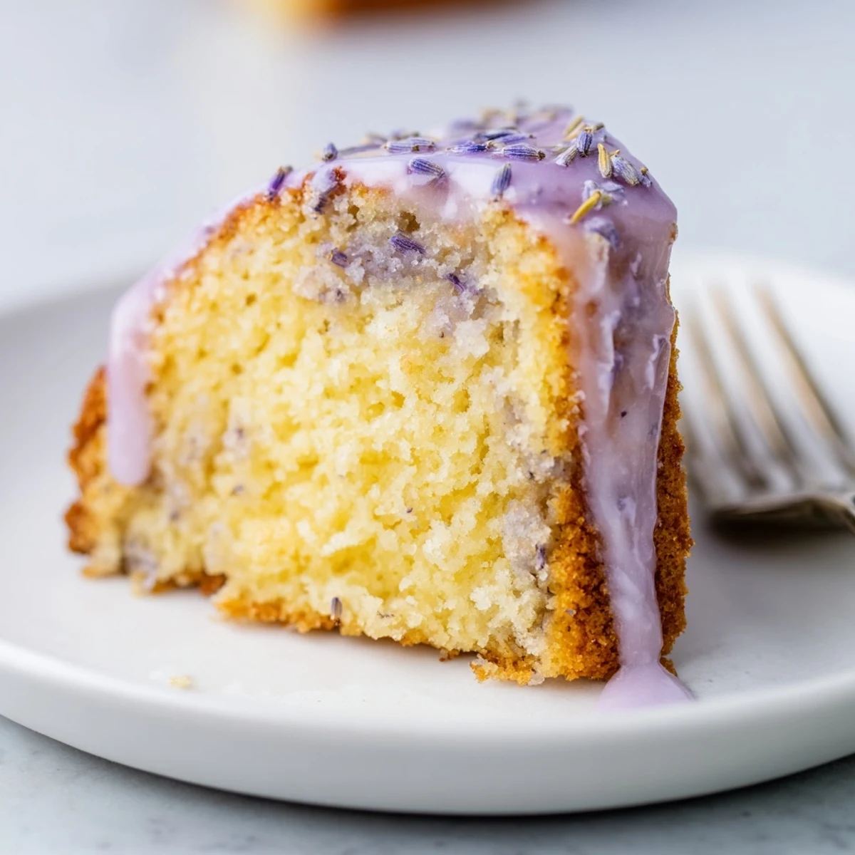Lavender cake with lemon glaze drizzled over a tender golden crumb flecked with purple buds