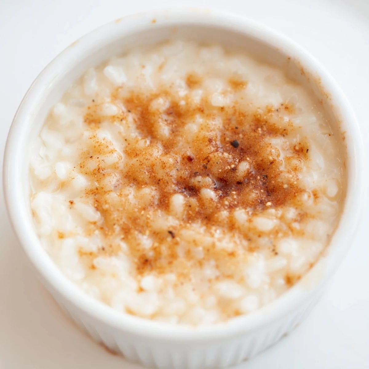 Creamy Portuguese rice custard topped with golden cinnamon sugar in white ramekins