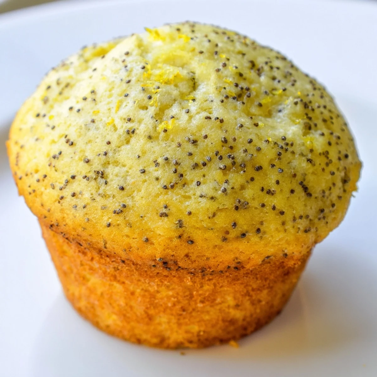 Moist lemon poppy seed muffins flecked with zest served warm on a rustic ceramic plate