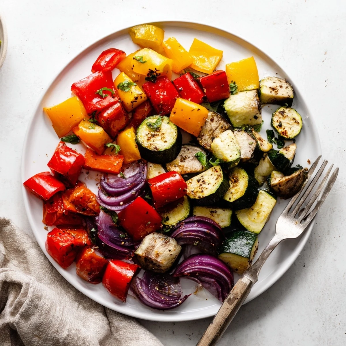 Colorful classic Mediterranean roasted vegetables with charred edges piled alongside fluffy quinoa.