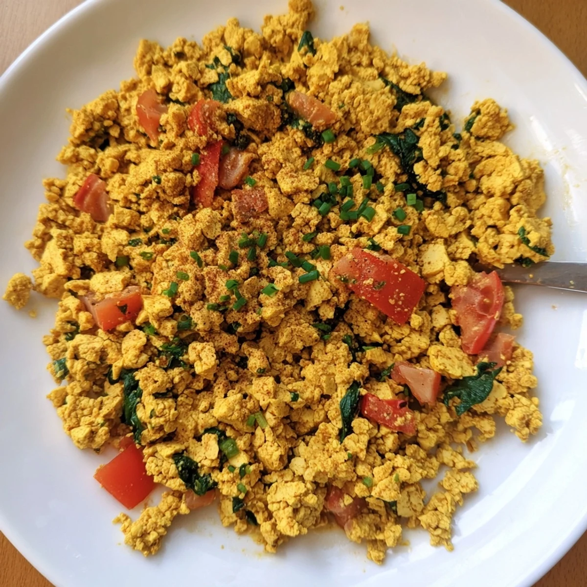 Bright Tofu Scramble studded with tomatoes and cumin, steaming on plate.