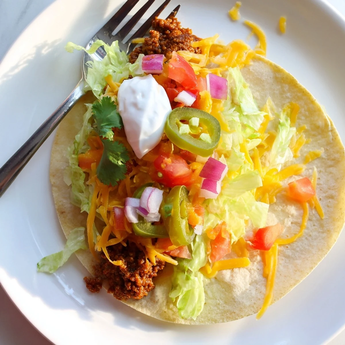 Blackstone griddle tacos featuring crispy seasoned beef layered with oozy cheese and colorful vegetables