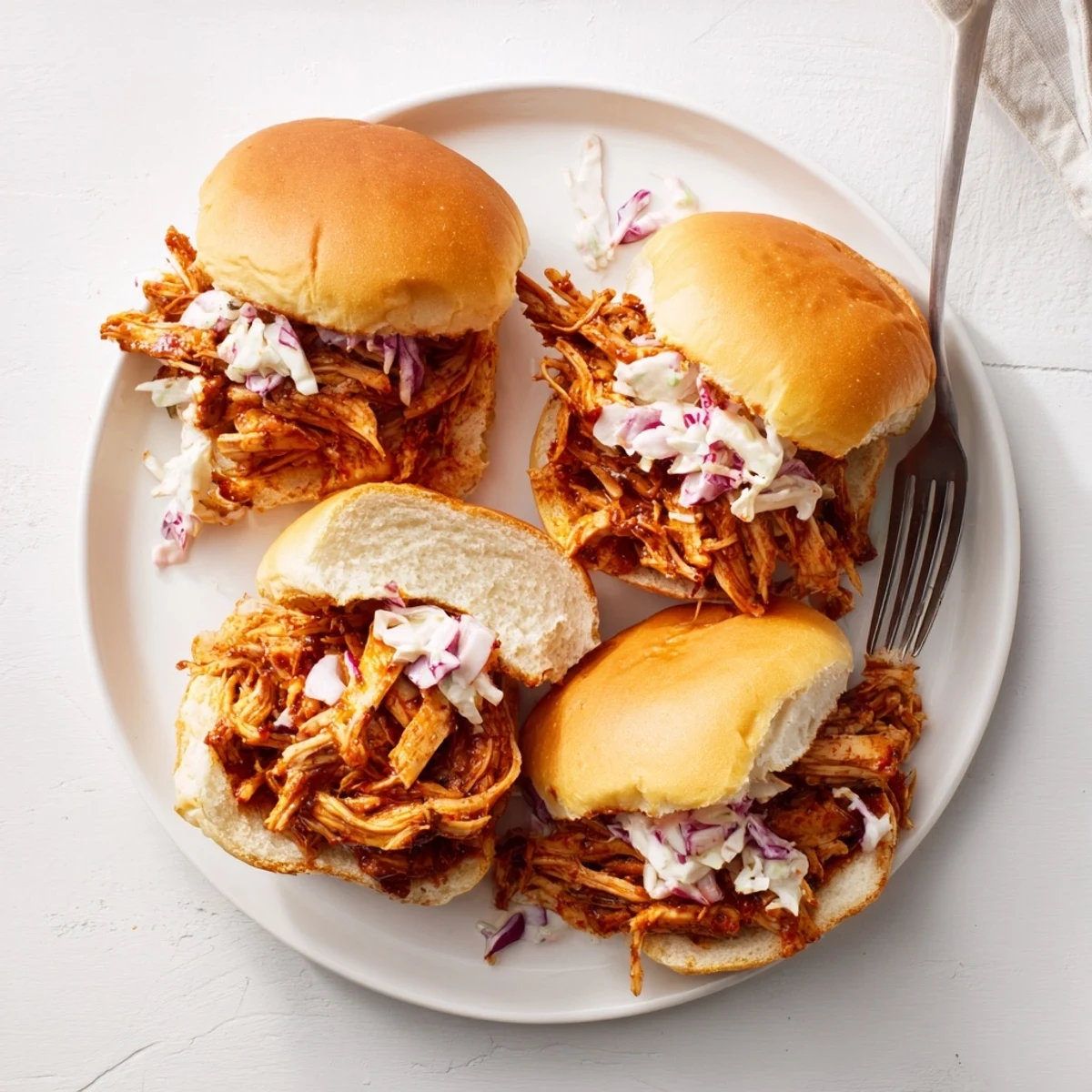 Easy BBQ Pulled Chicken Sliders with shredded meat and crisp coleslaw on soft rolls