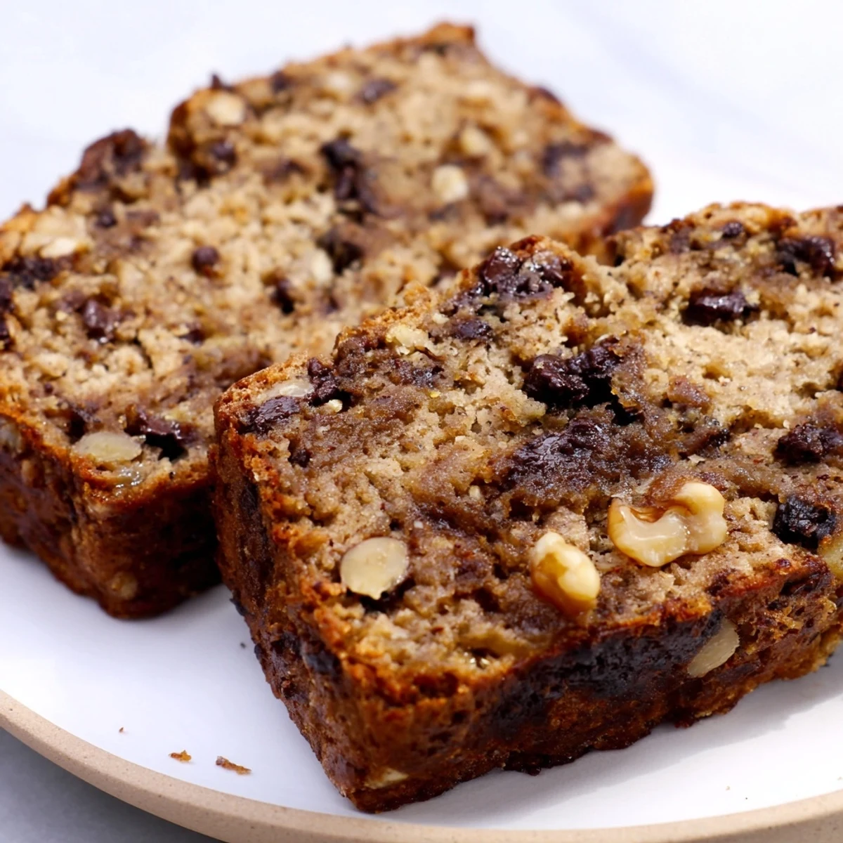 Moist wholesome protein banana bread oil free loaf sliced on a wooden cutting board with bananas