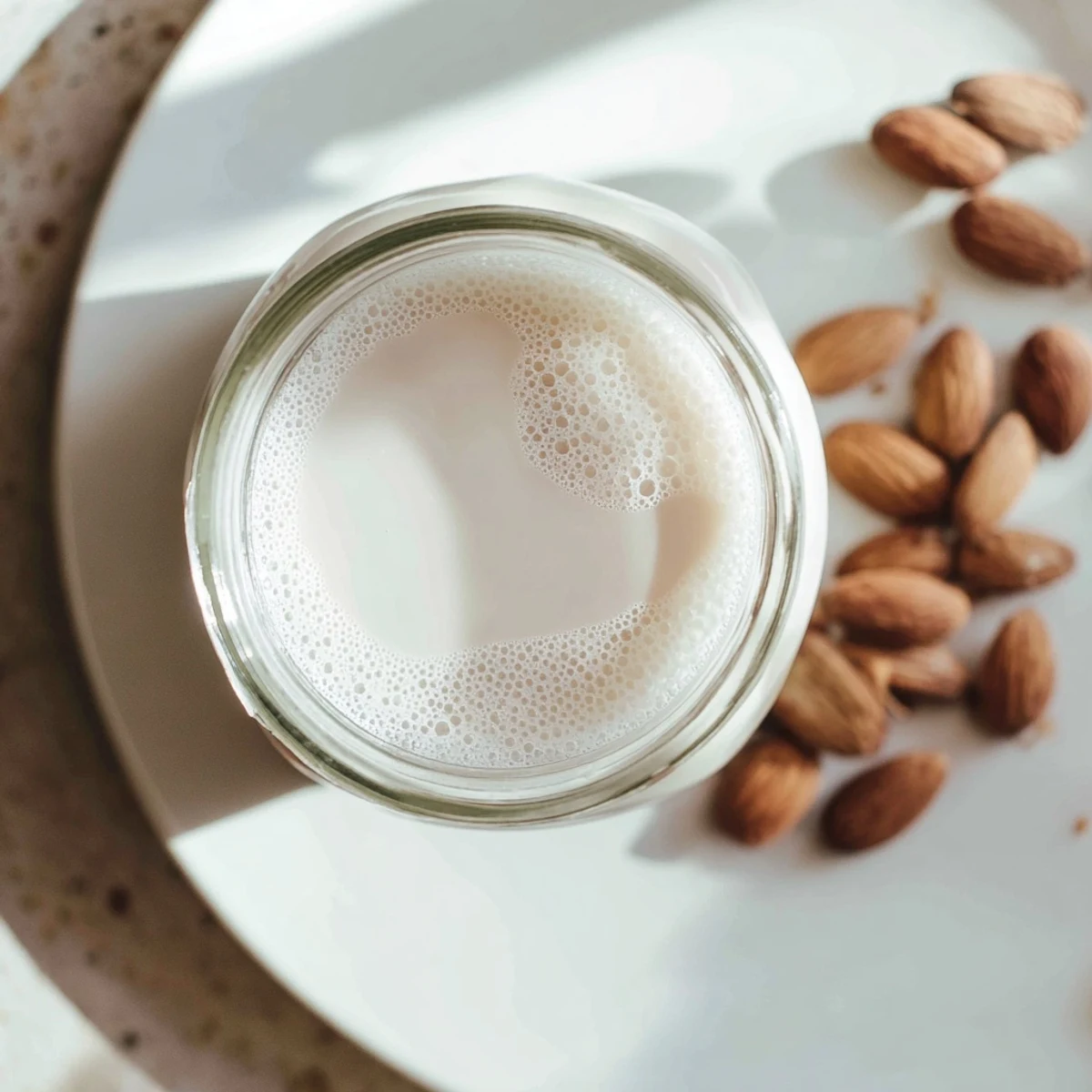 Homemade almond milk in mason jar with vanilla beans and stacked raw almonds