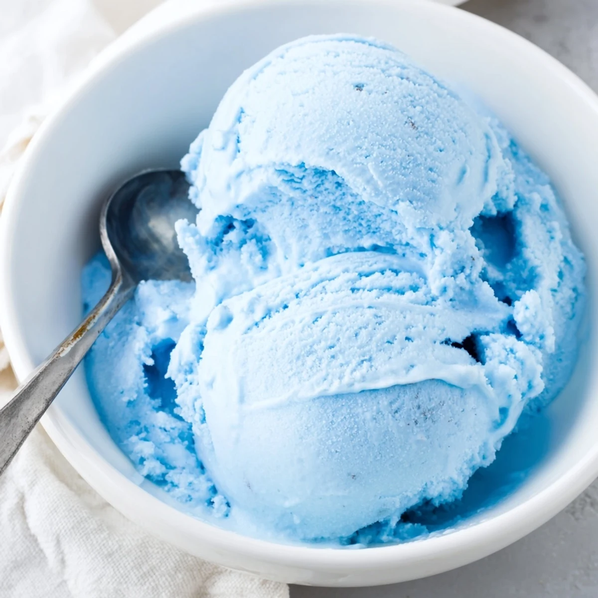 Creamy blue moon ice cream scooped into a crispy waffle cone with colorful sprinkles