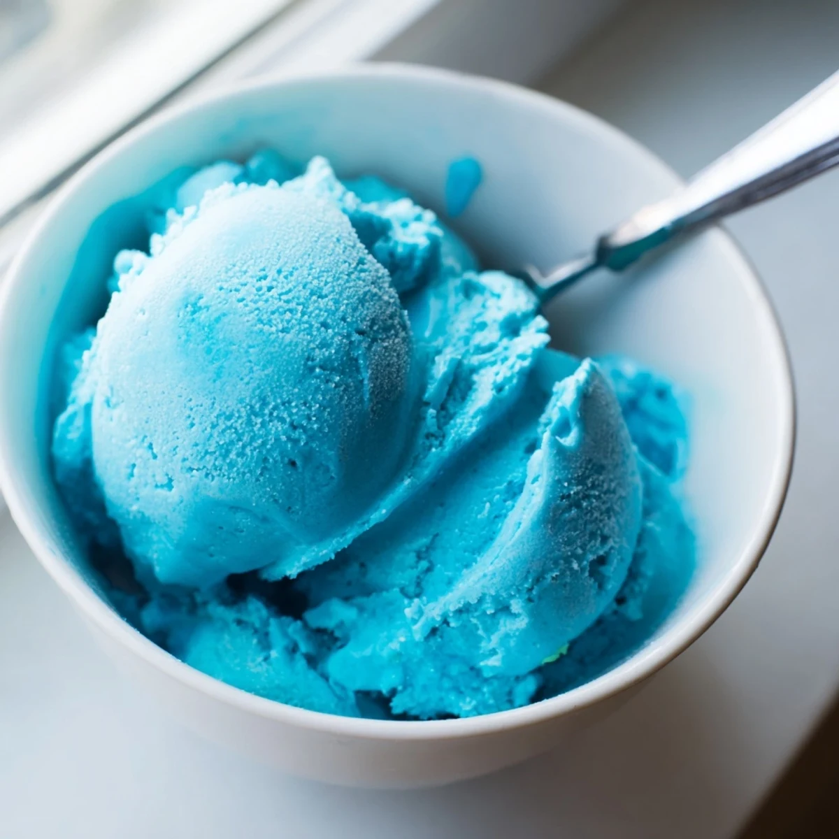 Vibrant blue moon ice cream served in a bowl topped with whipped cream