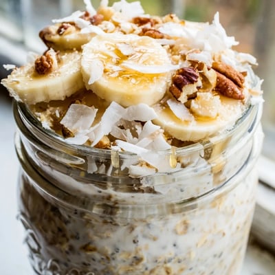 Thick coconut cream pie overnight oats in a mason jar with crunchy pecan topping